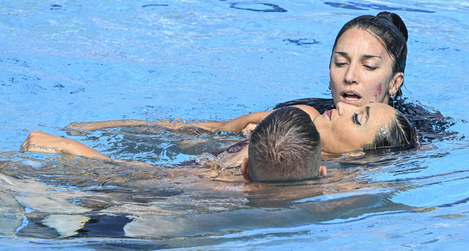 Anita Alvarezt edzője, Andrea Fuentes és egy segítő hozza ki a medencéből. szinkronúszás FINA vizes vb világbajnokság Budapest Magyarország 2022 baleset eszméletvesztés Anita Alvarez USA amerikai versenyző