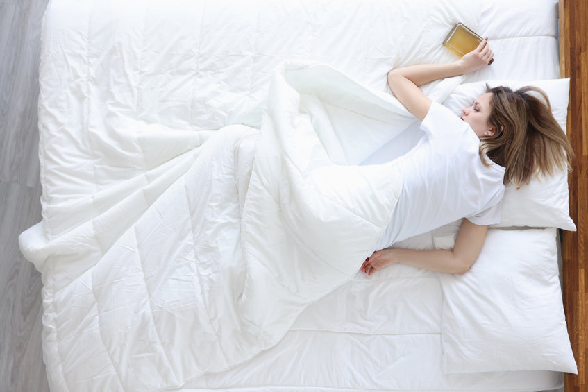 Fiatal nő hálószoba alvás párnák takarók fehér
