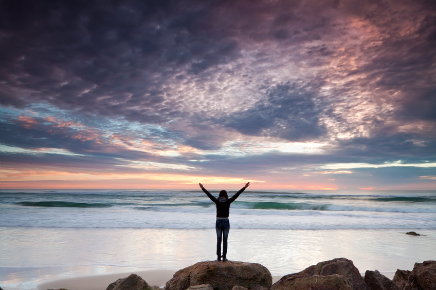 Fiatal nő egyedül áll a sziklán tengerparton