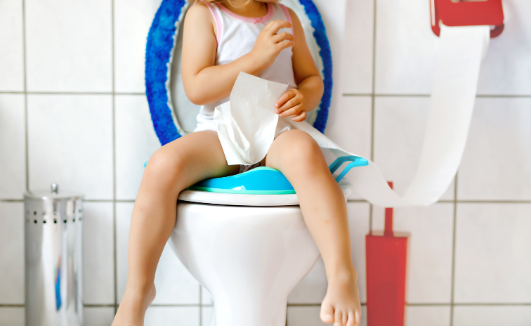 A kicsiket mindig saját tempójukban szoktassuk le a pelusról kisgyermek ül a wc-n kezében wc papírral