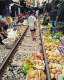 Út, piac és igen, jól látod, vasúti vonal is egyben a thaiföldi Maeklong Market Railway. Az árusok a sínek mentén kínálják a portékáikat, de ha jön a vonat, mindenki utat enged neki. Amint a jármű elzakatol mellettük, folytatódhat a piaci élet. 